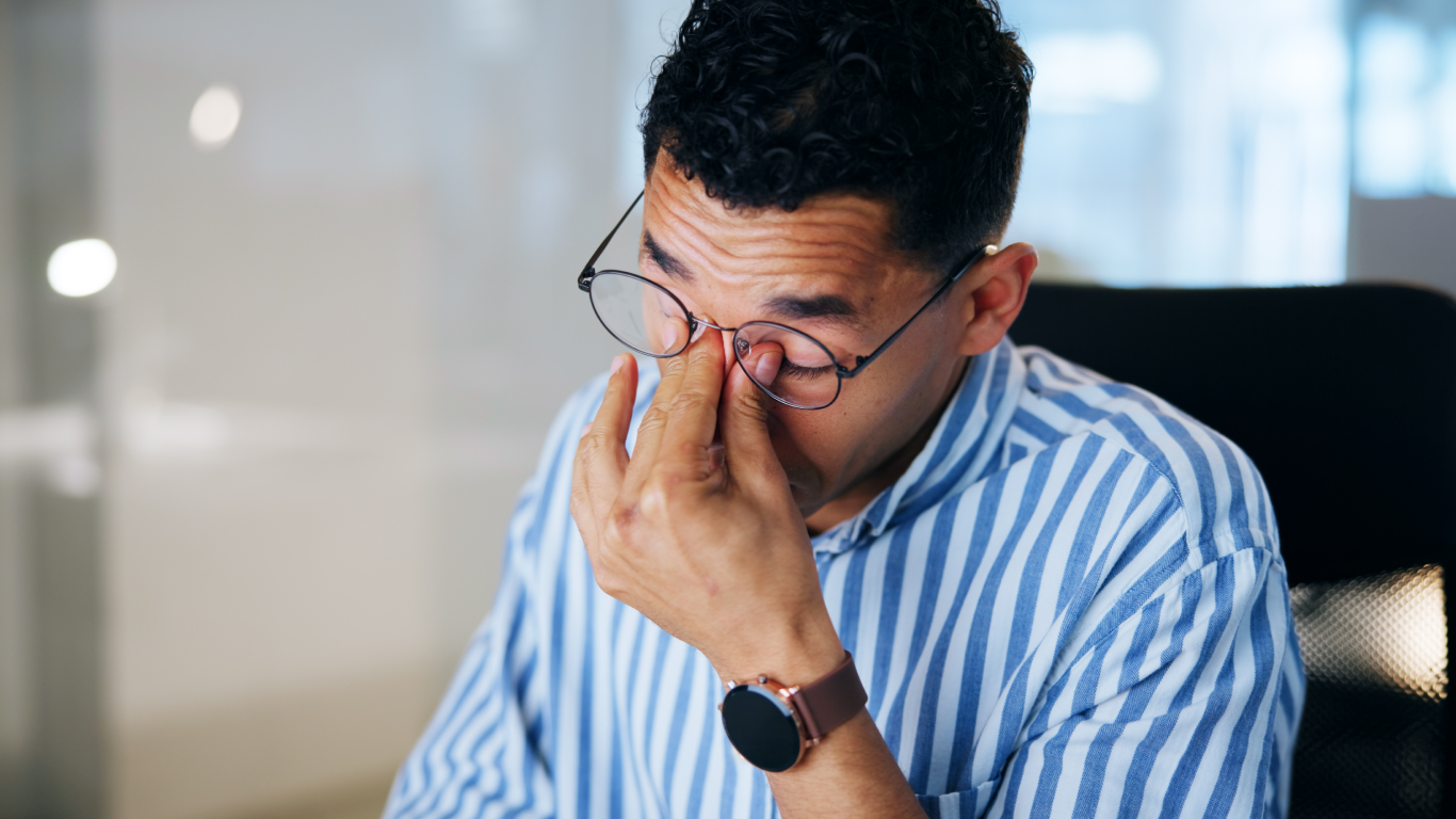 Homem com dor nos olhos, pensando em procurar um oftalmologista
